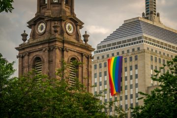 A rainbow pride flag hangs from a Boston building in celebration of the annual Pride Parade. Boston is on our LGBTQ+ itinerary because it is accepting and has lots of activities to do.