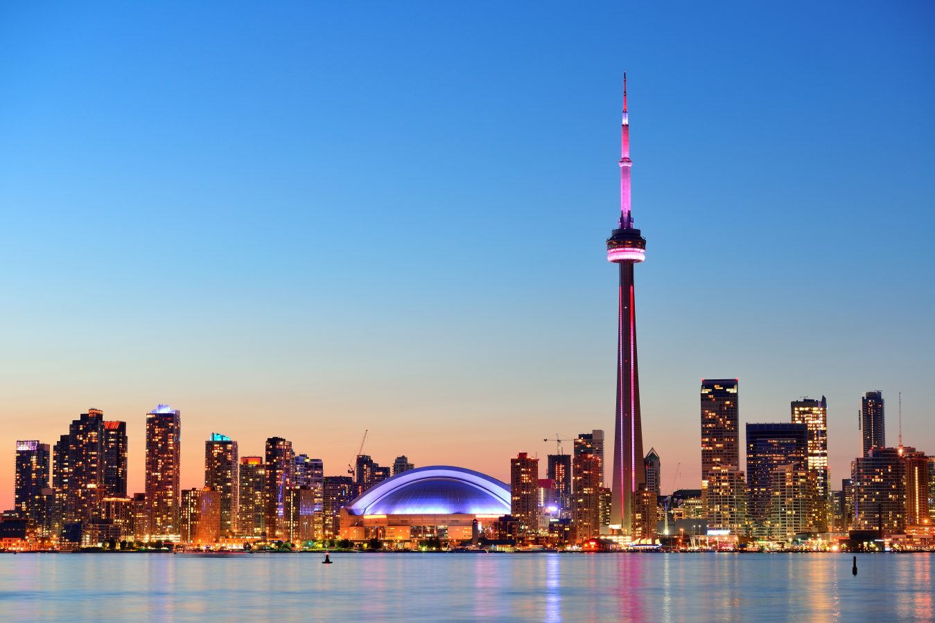 Toronto sunset over lake panorama with urban skyline.